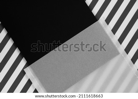 Mat cardboard black label tag for items or business card dressed in transparent white paper case in center on white and black zebra background. Tag mock up. Copy space.