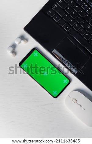 Flat lay shot of gadgets and mobile devices in white background. Smartphone green screen mockup