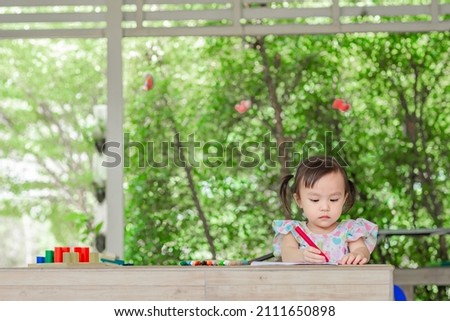 Little asian girl coloring cartoons on coloring book at home. Coloring Book Education Talent Concept. Copy space.