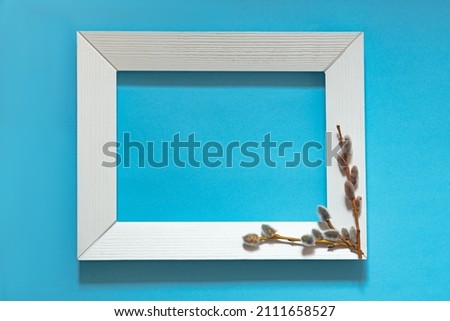 white frame with willow branches on a blue background, blooming buds, happy easter concept
