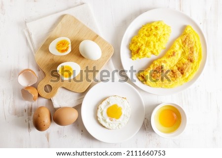 Cooking eggs in deferent way like boiled egg, fried egg and scrambled egg on wooden table. Top view. Royalty-Free Stock Photo #2111660753