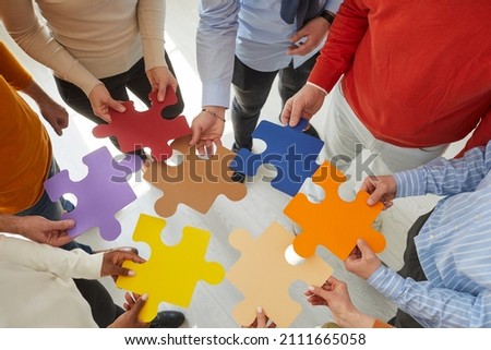 Close up top view of diverse multiracial businesspeople hold jigsaw pieces connect puzzle seek for business solution in office. Employees or colleagues involved in teambuilding activity or training. Royalty-Free Stock Photo #2111665058