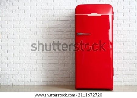Red fridge near white brick wall