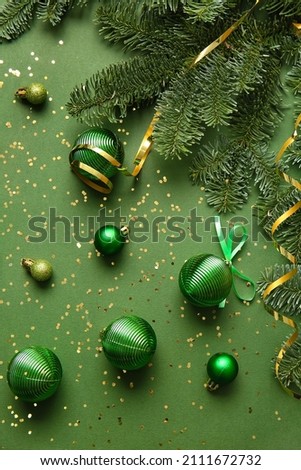 Christmas balls and fir branches on green background
