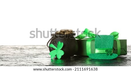 Pot with coins, gift box and leprechaun's hat on table against white background. St. Patrick's Day celebration