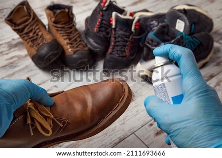 Processing of shoes with impregnation of water protection. Cleans the shoes in the autumn winter period Royalty-Free Stock Photo #2111693666