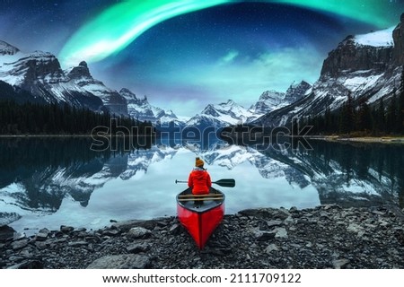 Traveler woman sitting on canoe with aurora borealis over Spirit Island in Maligne lake at Jasper national park, Alberta, Canada Royalty-Free Stock Photo #2111709122