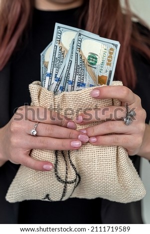 young serious girl in elegant stylish clothes holding earned dollar bills. The concept of earned money