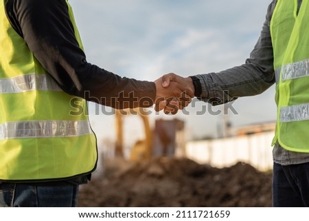 Engineers man handshake at construction site. Worker and contruction manager shaking hands while working for teamwork. Royalty-Free Stock Photo #2111721659
