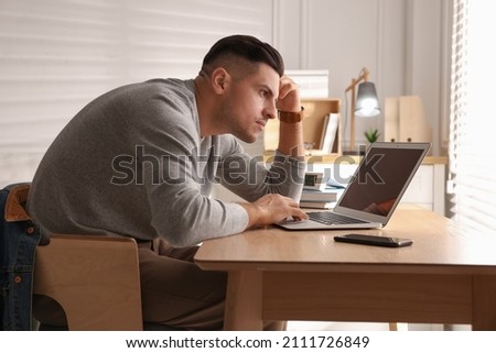 Man with poor posture using laptop at table indoors Royalty-Free Stock Photo #2111726849