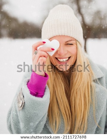 Attractive European blonde woman in winter with a heart made of ice - ice heart Valentine day - making snowballs to lovers Royalty-Free Stock Photo #2111727698