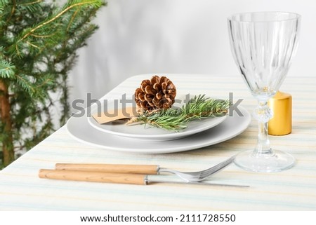 Beautiful table setting with pine cone and fir branch, and blank tag indoors