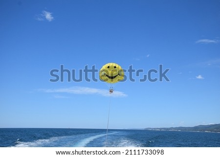 Russia, Sochi, Lazarevskoye settlement, August 10, 2018 : Tourists enjoy a summer vacation on the beach. Parachute flight. A sunny day. Rest. Blue sky. Sea entertainment. Smile. Parachute.