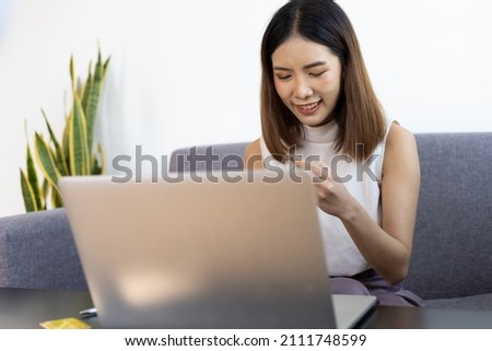 Asian woman working on laptop at home. Work from home and online shopping concept.