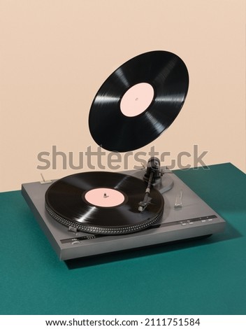 Retro composition of vinyl record player and floating record. Atmosphere of discos, good creative mood and aesthetics of luxurious rest. Royalty-Free Stock Photo #2111751584