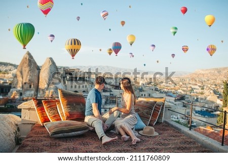 Happy young couple during sunrise watching hot air balloons in Cappadocia, Turkey Royalty-Free Stock Photo #2111760809