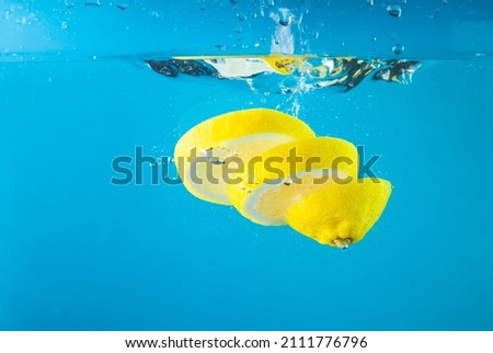  Cut fresh lemons in clear water with splash, blue background. High quality photo