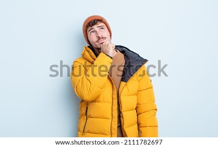 young handsome man thinking, feeling doubtful and confused. winter concept