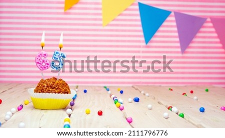 Happy birthday for 65 years old. Festive background with muffin. Copy space birthday card for sixty-five years on a pink background