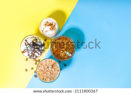 Set with different iced summer coffee drinks - espresso, frappe, latte, cappuccino, with whipped cream, syrup and crushed ice, in various glasses and  mugs on trendy bright yellow blue background