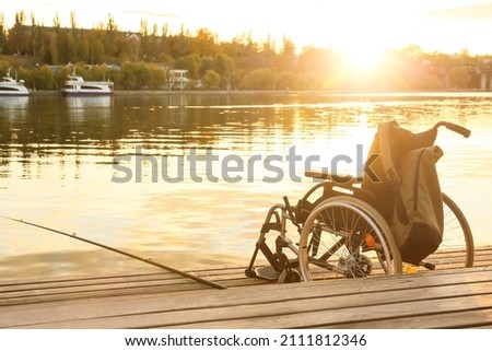 Wheelchair and fishing rod on pier near river