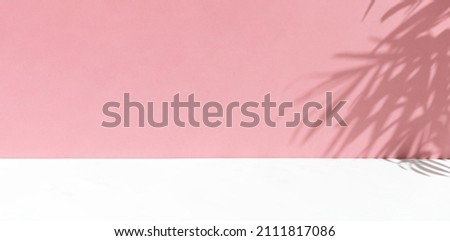 Minimal abstract background for the presentation of a cosmetic product. Premium podium with a shadow of tropical palm leaves on a pink wall and white table. Showcase, display case. Banner