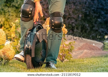 Rider's legs in protective gear on an electric unicycle (EUC). Driving around the city on an electric monowheel. Royalty-Free Stock Photo #2111819012
