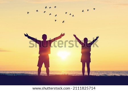 Couple raise hand up on sunset sky at beach and island with birds flying abstract background. Freedom and travel adventure concept. Vintage tone filter color style.