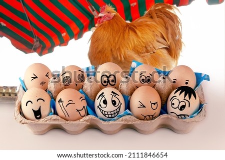 Eggs with different faces in eggbox and and a Orpington Hen, Rooster as advertising. Types of temperaments. Sanguine, choleric, angry, phlegmatic, happy or melancholic. Face illustrated on eggs