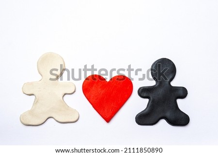 Small black and white plasticine men hold a red plasticine heart in their hands on a white background
