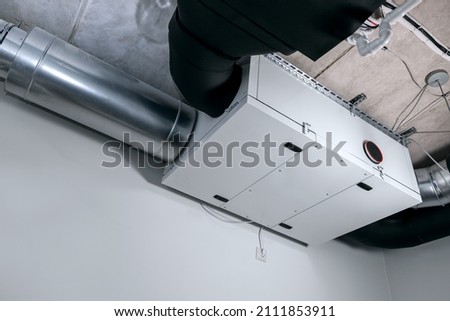 modern heat recovery ventilation system mounted on ceiling in house service room. recuperator Royalty-Free Stock Photo #2111853911