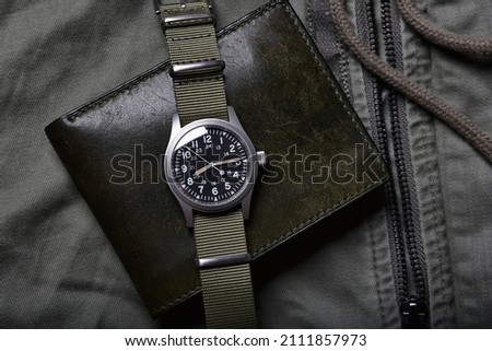 Vintage military watch and leather wallet on army green background, Classic timepiece mechanical wristwatch, Men fashion and accessories. Royalty-Free Stock Photo #2111857973