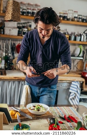 man preparing food in his kitchen. he is taking photo of dish