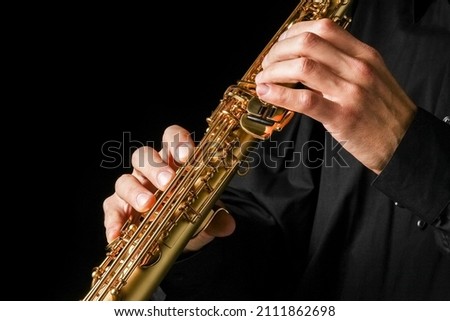 soprano saxophone in hands on a black background Royalty-Free Stock Photo #2111862698