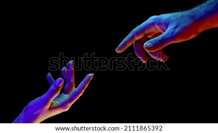 Idea of earth creation. Hands reaching out, pointing finger together on black and neon colorful light. Man and woman, love, religion. Contemporary art, evolution, origins concept. Royalty-Free Stock Photo #2111865392