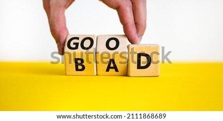 Good or bad symbol. Businessman turns wooden cubes and changes the word bad to good. Beautiful yellow table, white background, copy space. Business and bad or good concept. Royalty-Free Stock Photo #2111868689
