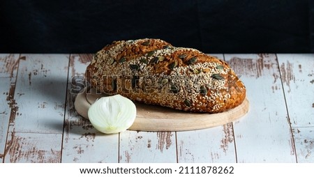Top view of loaf with sesame seeds, pumpkin seeds and onion on a wooden board