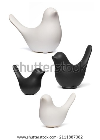 Detail shot of figurines of black and white matte birds with raised tails.  The porcelain statuettes are isolated on the white background.
