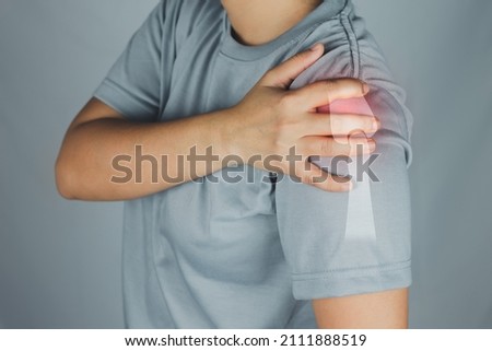 Health concept, person has left shoulder pain, woman uses right hand to hold left shoulder due to shoulder pain, virtual bone image on shoulde Royalty-Free Stock Photo #2111888519