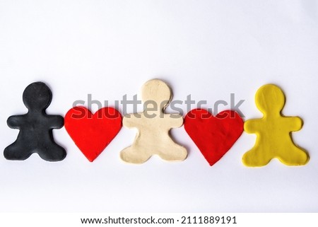 Three black, white and yellow plasticine men hold red platinum hearts in their hands on a white background. Diverse family concept. Relationship concept. Symbolism and minimalism