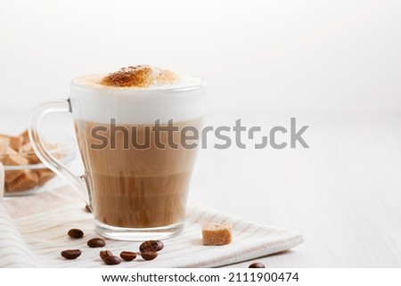 Latte coffee poured in layers with froth and a crispy chocolate top on a light kitchen table, copy space Royalty-Free Stock Photo #2111900474