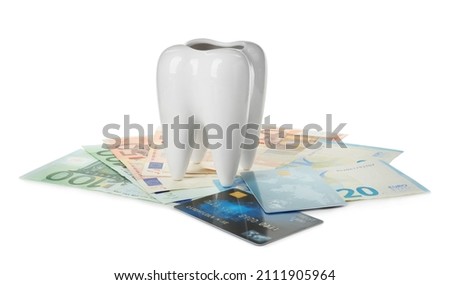 Ceramic model of tooth, euro banknotes and credit cards on white background. Expensive treatment