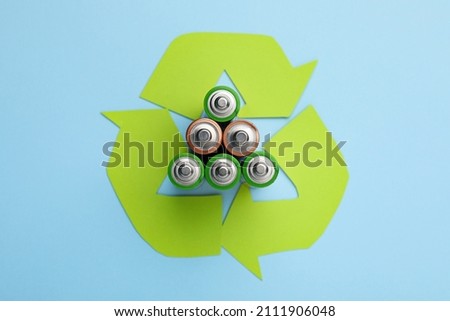 Used batteries and recycling symbol on light blue background, flat lay