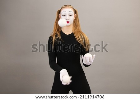 The mime artist juggles balls. Circus clown woman. On a gray background.