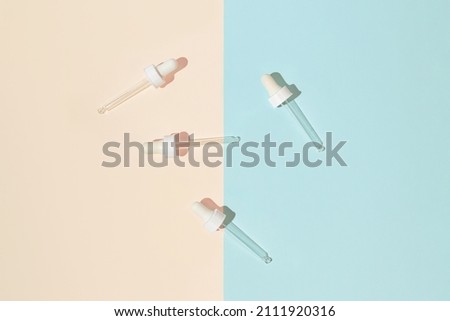 Serum droppers on geometric background. Skin care and cosmetic concept. Beauty rituals theme. Top view. Flat lay. Minimal style