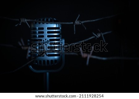 Microphone behind barbed wire as a symbol of discrimination, free speech crisis, political persecution and repression.