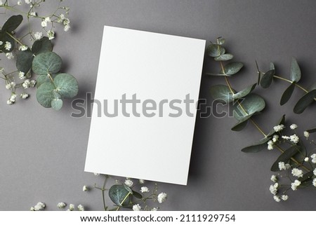 Wedding invitation or greeting card mockup with eucalyptus and gypsophila twigs, top view