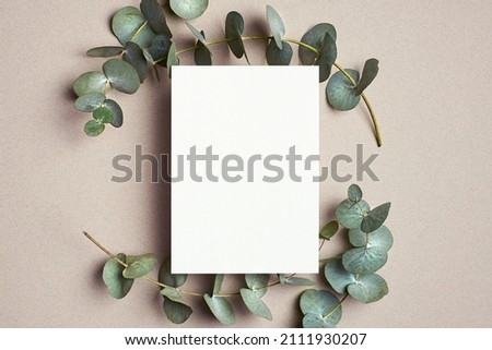 Greeting or wedding invitation card mockup with natural eucalyptus twigs. Blank card with copy space.