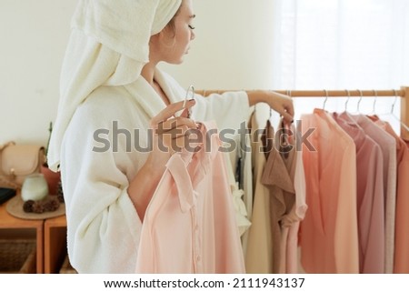 Cropped image of woman choosing clothes to wear after morning shower Royalty-Free Stock Photo #2111943137