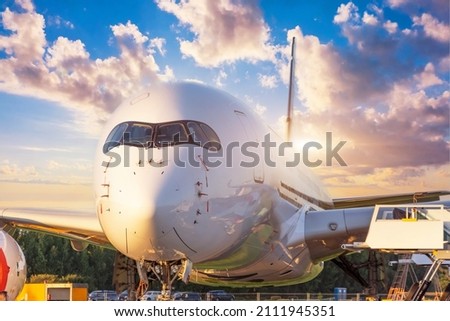 The cockpit of the nose and fuselage of the aircraft against the background of the evening sky with beautiful clouds Royalty-Free Stock Photo #2111945351